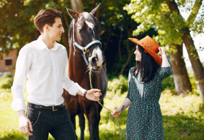 Couple in a summer park. Pair standing with a horse. Girl in a green dress