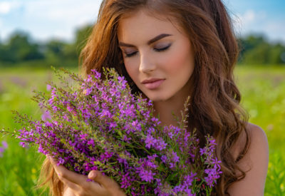 Closeup portrait of a caucasian woman relaxing on nature. Young woman outdoors with a bouquet. Girl in a field with lavender flowers in her hands.