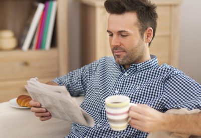 Smiling man with newspaper and cup of coffee