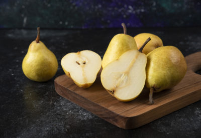 Wooden board of delicious yellow pears on black surface. High quality photo