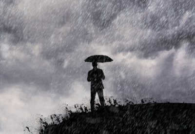 Silhouette of man standing with umbrella in the rain