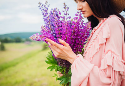 Woman in hay hat poses with bouquet of lavander on the field