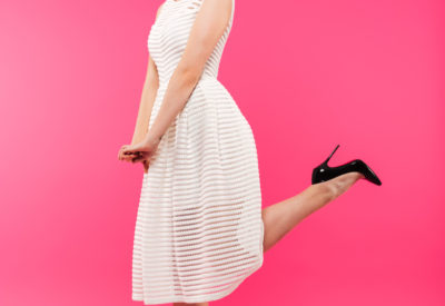 Full length portrait of a lovely girl dressed in dress posing while standing isolated over pink background